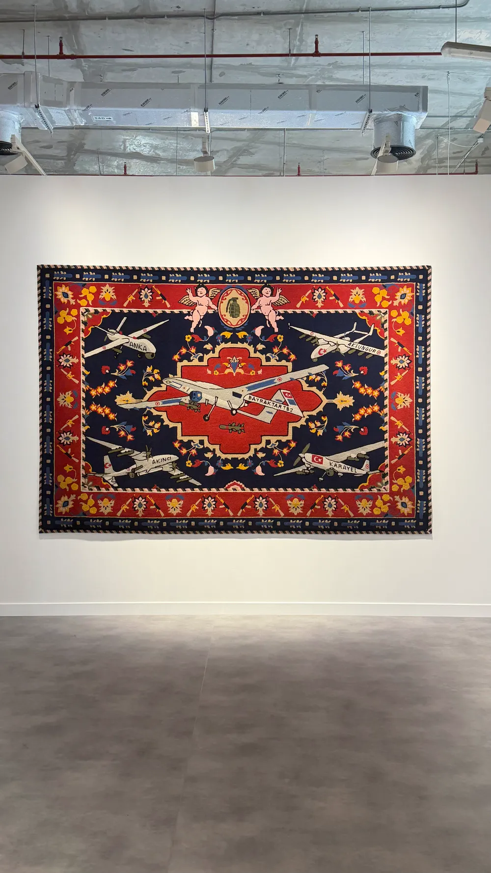 Art Basel Katar’da Halil Altındere’nin Turkish Military Drones Rug adlı çalışması, askerî insansız hava araçlarını motif olarak kullanan büyük ölçekli dokuma halı formunda sergileniyor.