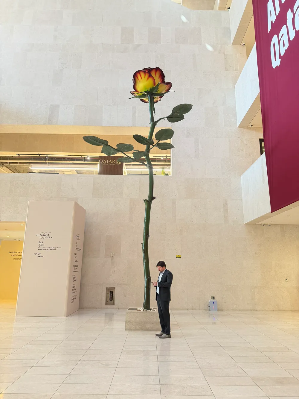 Art Basel Katar’da Isa Genzken’e ait, iç mekânda sergilenen büyük ölçekli tek gül formundaki heykel önünde bir ziyaretçi yer alıyor.