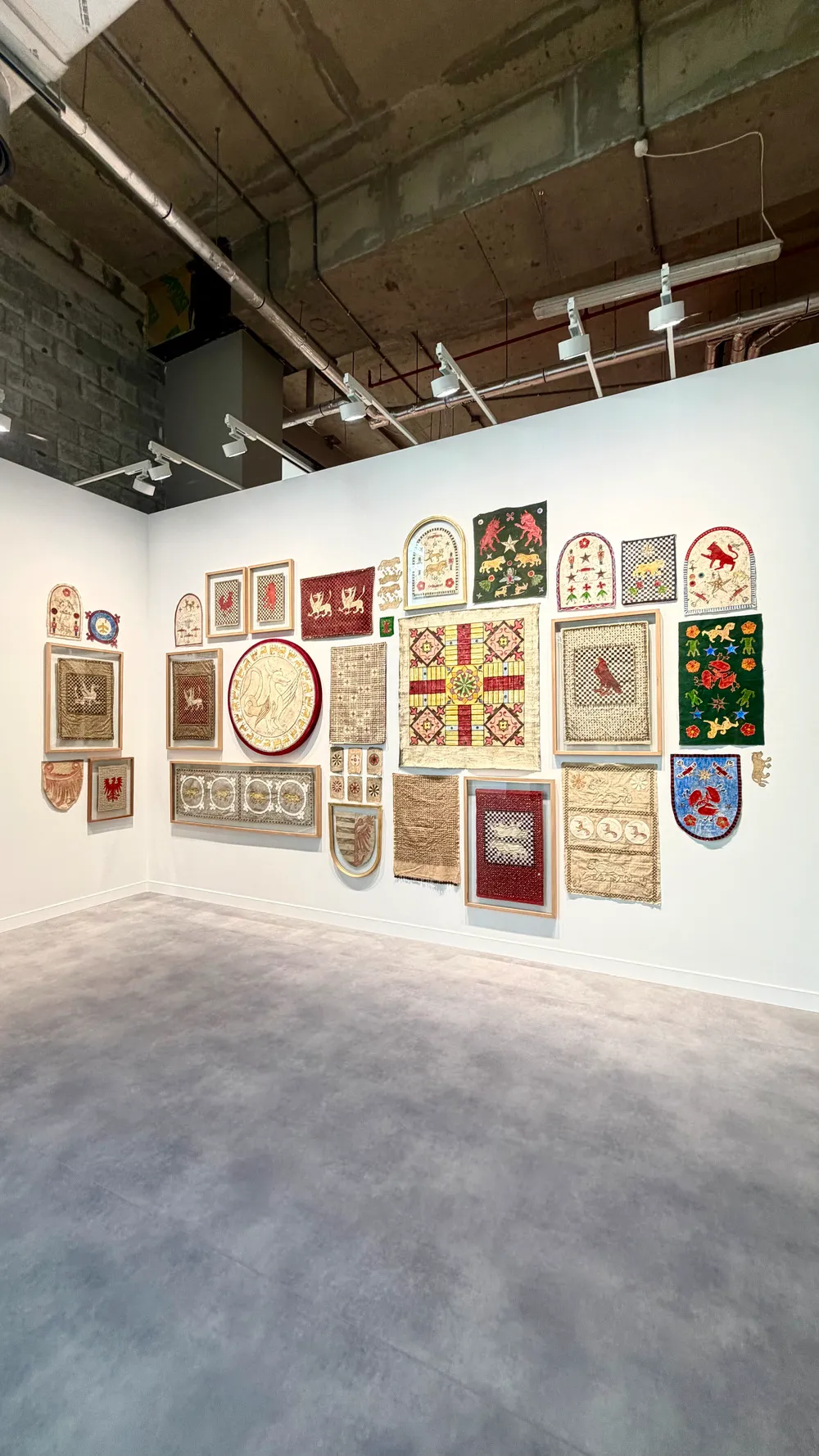 Art Basel Katar’da Mohamed Monaiseer’e ait, tekstil ve nakış temelli farklı ölçeklerde işlerin bir duvar boyunca birlikte sergilendiği yerleştirme.
