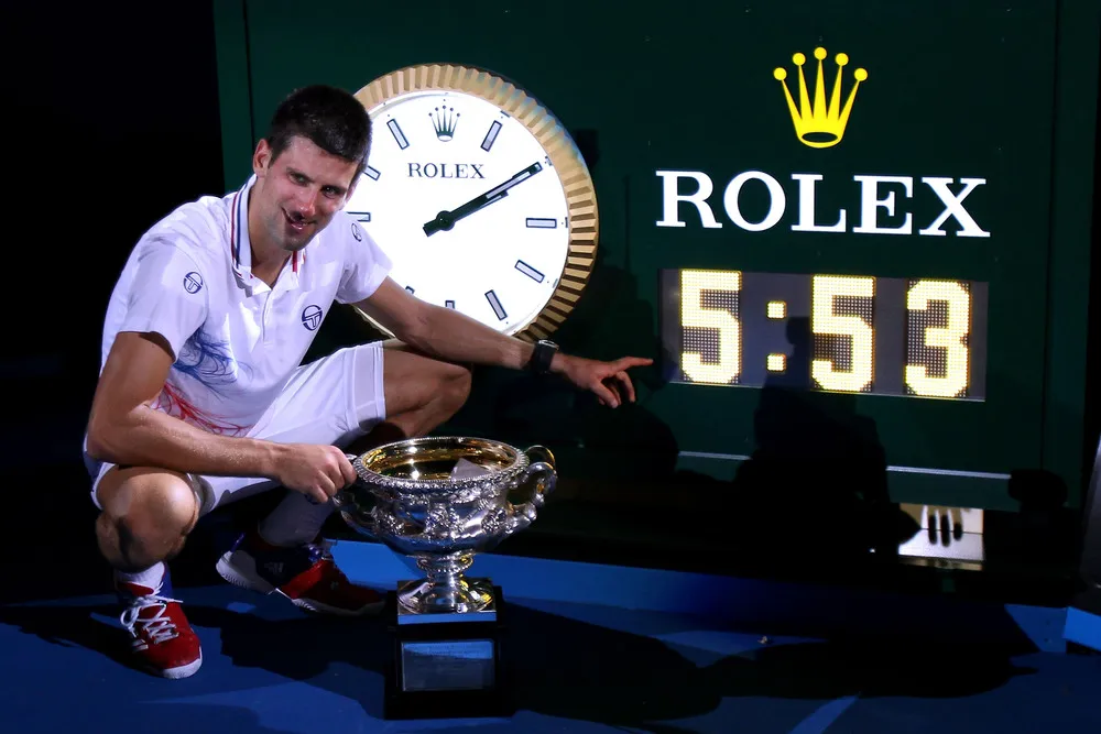 2012 Australian Open finali sonrası Norman Brookes Challenge Cup ve maç süresini gösteren saatle poz veren Novak Djokovic