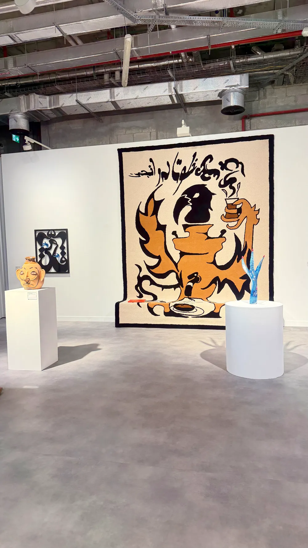 Art Basel Katar’da Raster Galeri standında Slavs and Tatars kolektifine ait, yazı ve figür öğelerini bir araya getiren büyük ölçekli duvar işi ve heykeller.