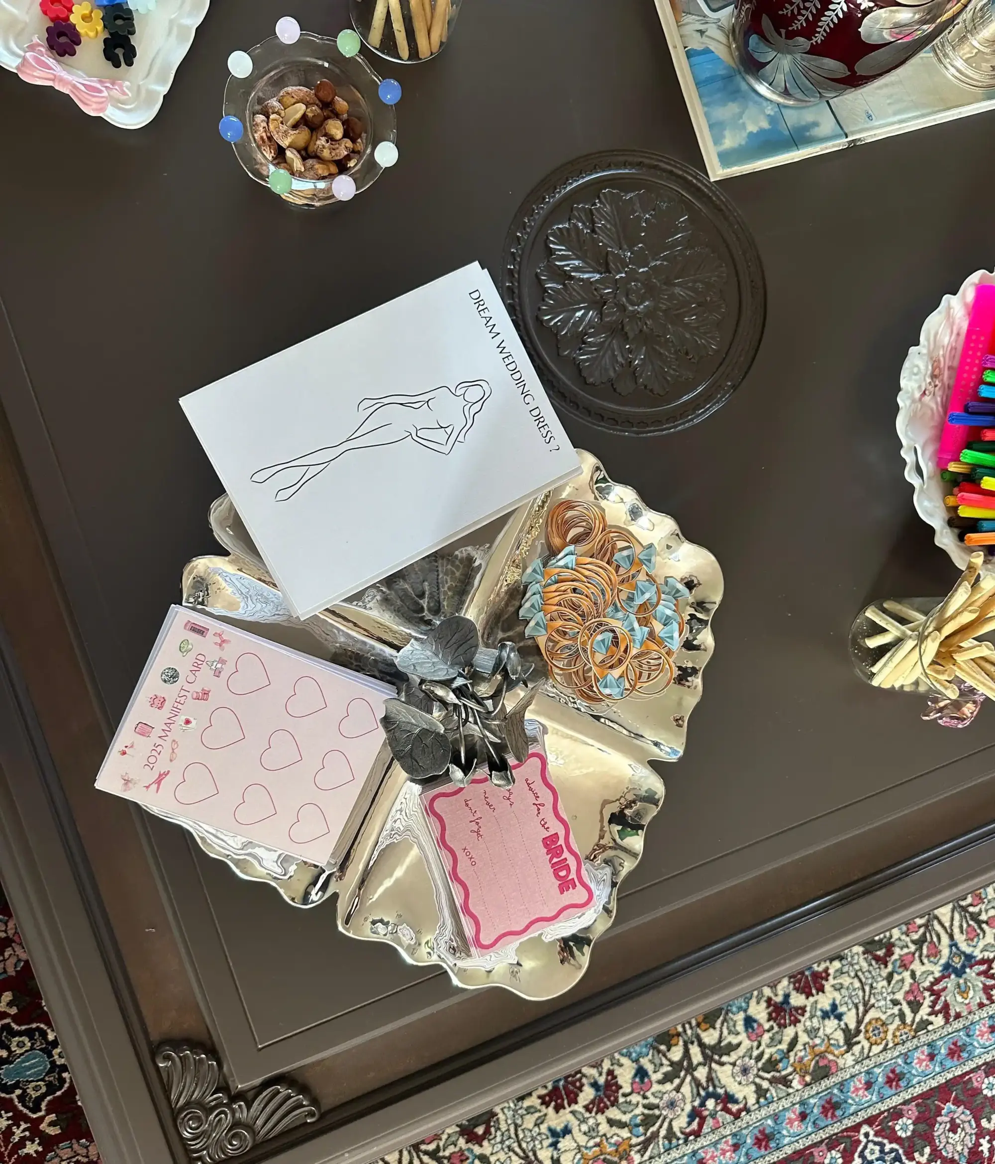 Bridal shower etkinliğinde masa üzerinde yer alan “Dream Wedding Dress?” tasarım kartı, bride not kartı, elastik tokalar, kuruyemişler ve yaratıcı workshop malzemeleriyle hazırlanmış şık ve detaylı organizasyon düzeni.