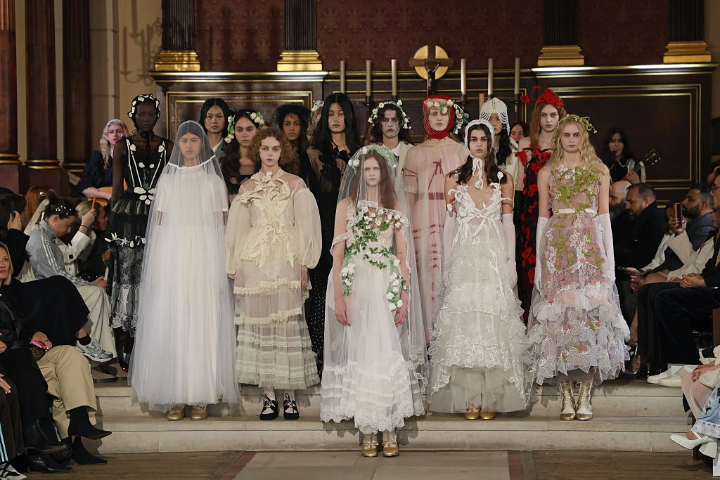 Bora Aksu 2026 Sonbahar-Kış koleksiyonunda transparan tül katmanlar, dantel işlemeler, floral detaylar ve romantik Victorian ilhamlı tasarımlarla şiirsel ve dramatik couture siluetler.