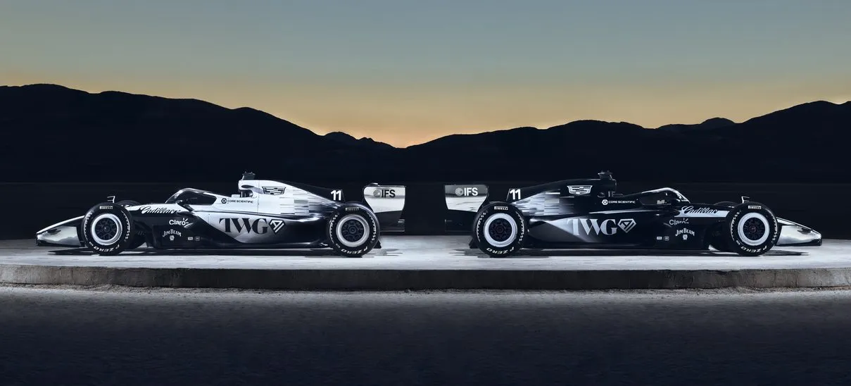 Cadillac F1 Team’in siyah-gümüş renkli iki Formula 1 aracı, gün batımı fonunda yan yana konumlandırılmış stüdyo çekimi.