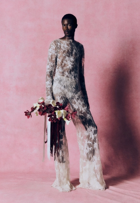Harris Reed 2026 Sonbahar-Kış koleksiyonunda transparan dantel tulum ve floral buketle modern bridal estetiğini yeniden yorumlayan avangart siluet.