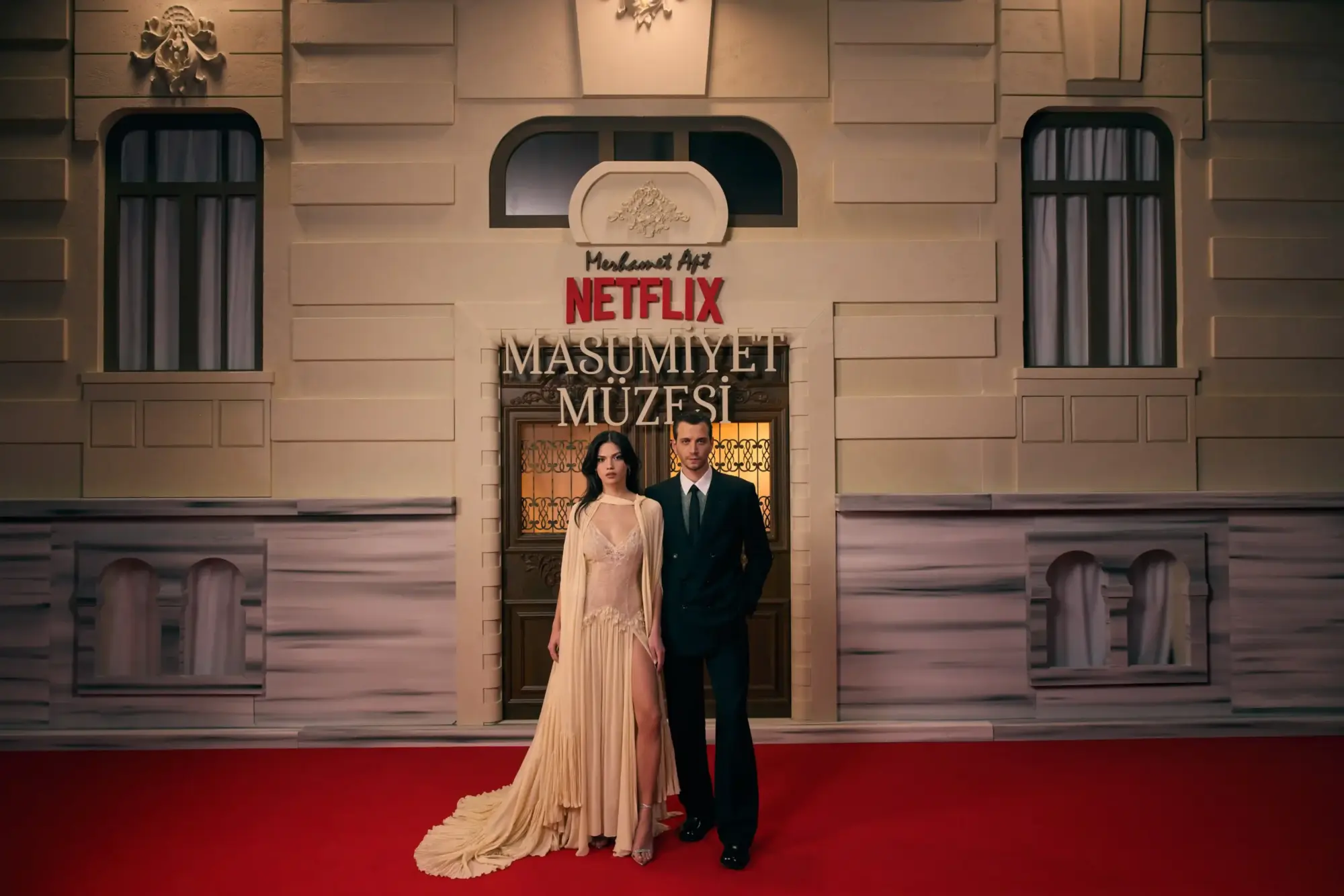 Netflix “Masumiyet Müzesi” galasında kırmızı halıda poz veren Eylül Lize Kandemir ve Selahattin Paşalı; arkada dizi logosu ve tarihi bina cephesi.