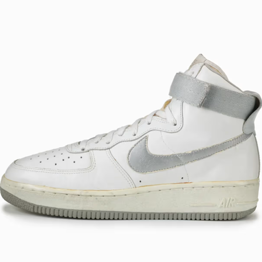 Beyaz ve gri detaylara sahip Nike Air Force 1 High spor ayakkabı modeli, yan açıdan beyaz fonda ürün çekimi.