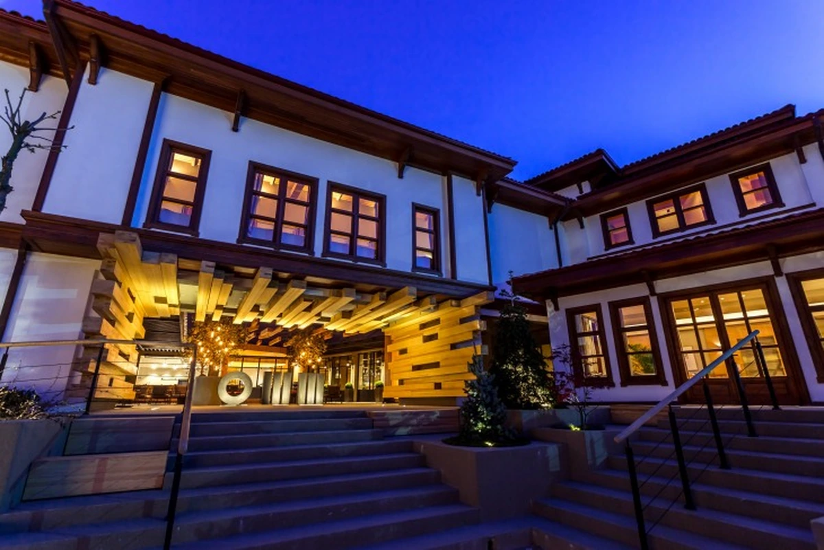 Odunpazarı'nın karakteristik ahşap detaylarını ve beyaz cephesini yansıtan Omm Inn otelinin modern ışıklandırmalarla aydınlatılmış, davetkar girişi ve pencerelerinden sızan sıcak ışıklarla parlayan zarif dış cephesi, alacakaranlıkta göz kamaştırıyor.