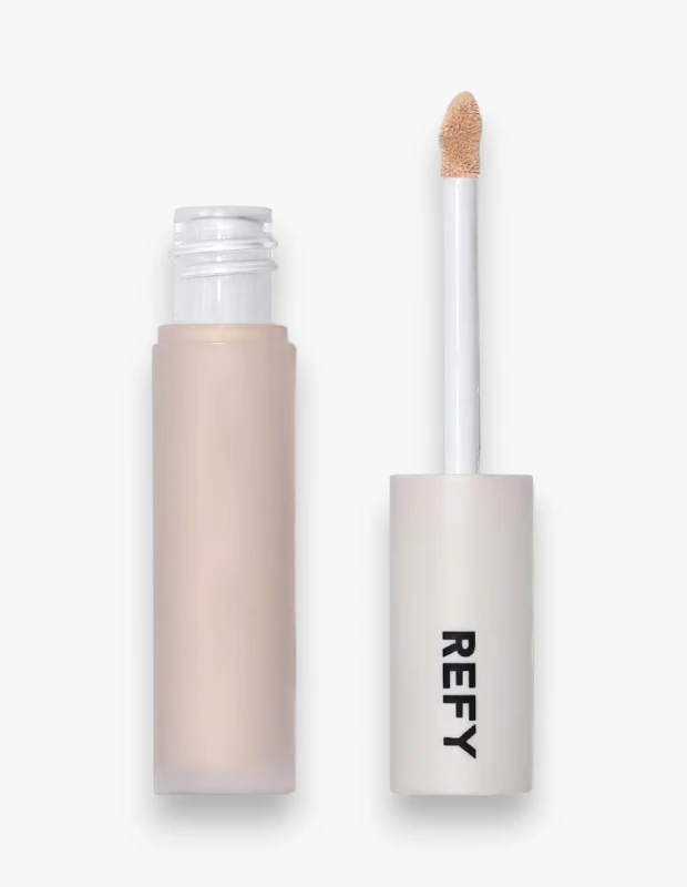 Refy aydınlatıcı ve bulanıklaştırıcı serum kapatıcı, beyaz bir arka plan üzerinde dikey konumlandırılmış, bej renkli mat görünümlü şişesi açık şekilde ve ucunda hafif tonda ürün bulunan sünger aplikatörü yanı başında gösteriliyor.