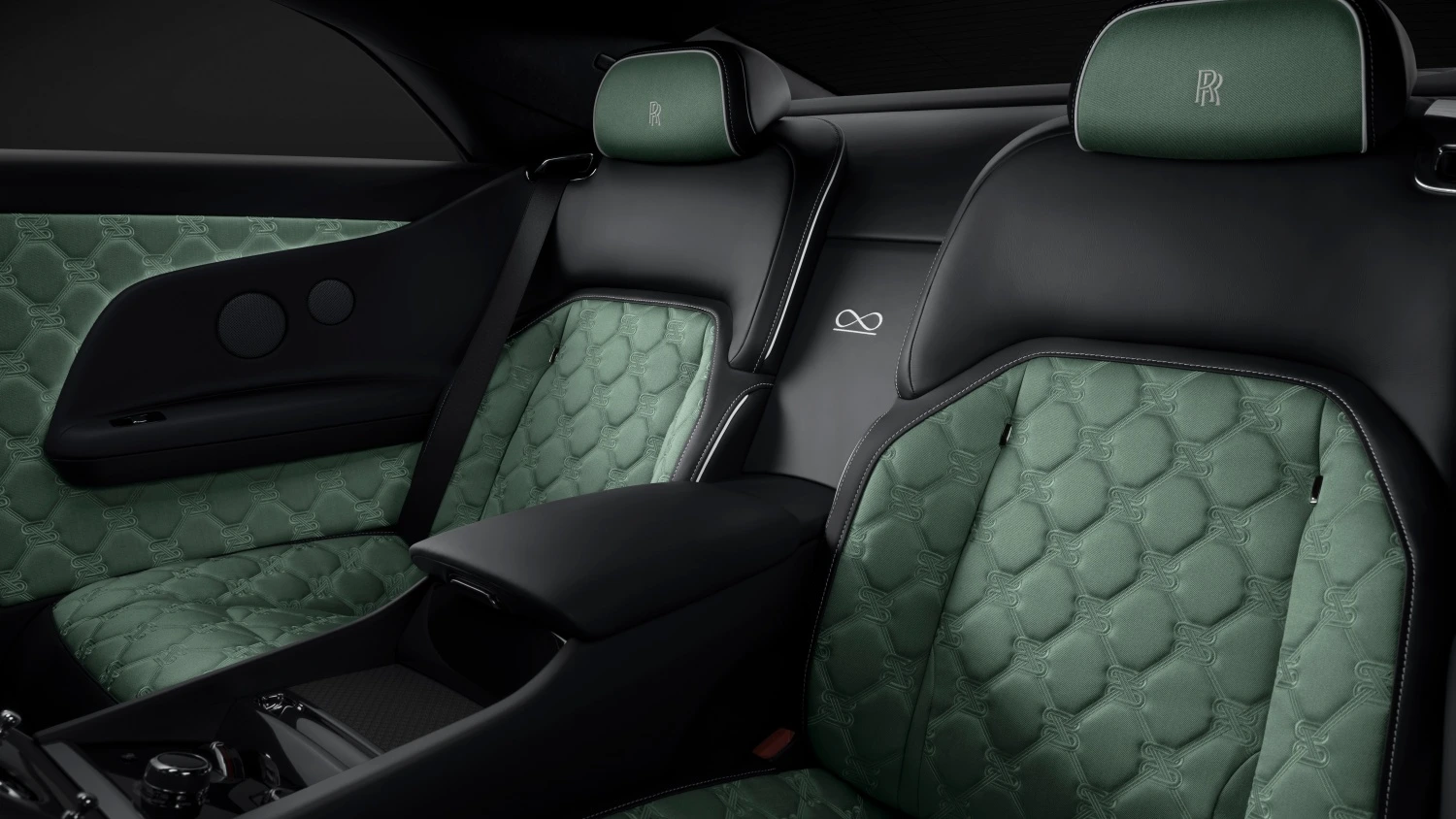 Rolls-Royce Spectre Black Badge modelinin arka koltuklarının görüldüğü bu iç mekan görüntüsünde, yeşil ve siyah renkli lüks deri döşemeler, özel kapitone deseni, entegre RR monogramları ve zarif el işçiliği ile aracın prestijli atmosferini vurguluyor.