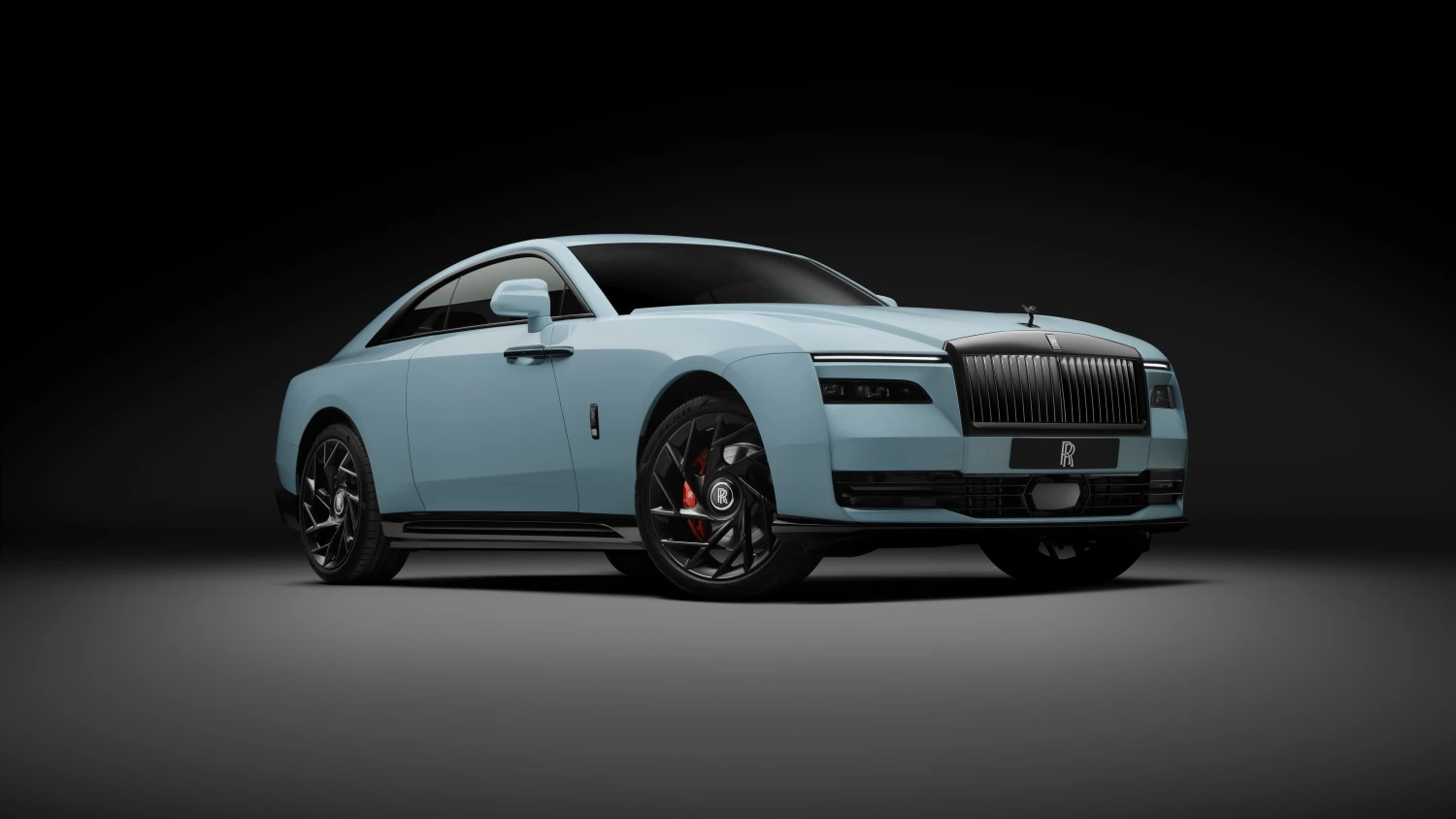 Rolls-Royce Spectre Series 2 Black Badge elektrikli lüks otomobilin koyu bir stüdyo ortamında önden çapraz açıyla çekilmiş fotoğrafı; buz mavisi gövdesi, parlak siyah aerodinamik jantları ve kırmızı fren kaliperleriyle modern ve güçlü bir görünüm sergiliyor.