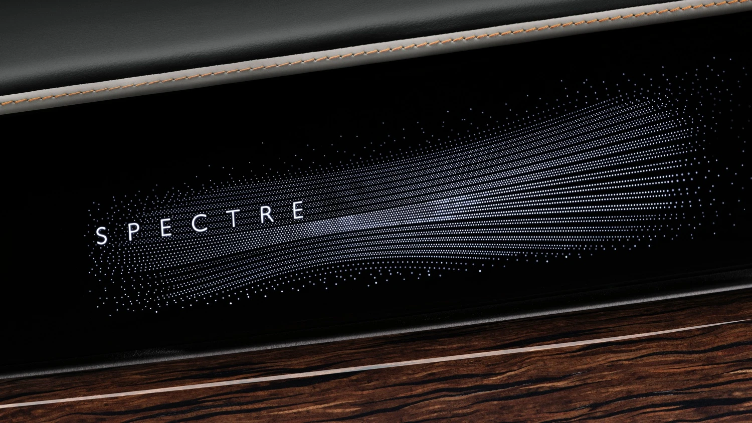 Makyajlı Rolls-Royce Spectre Series 2'nin iç mekanından bir detay, ön konsolda SPECTRE yazısının ve sağa doğru yayılan parlak nokta deseninin ışıklandırıldığı, üst kısmında açık renk dikişli koyu renk deri, alt kısmında ise parlak ahşap detaylarla çevrili modern ve lüks bir panel.