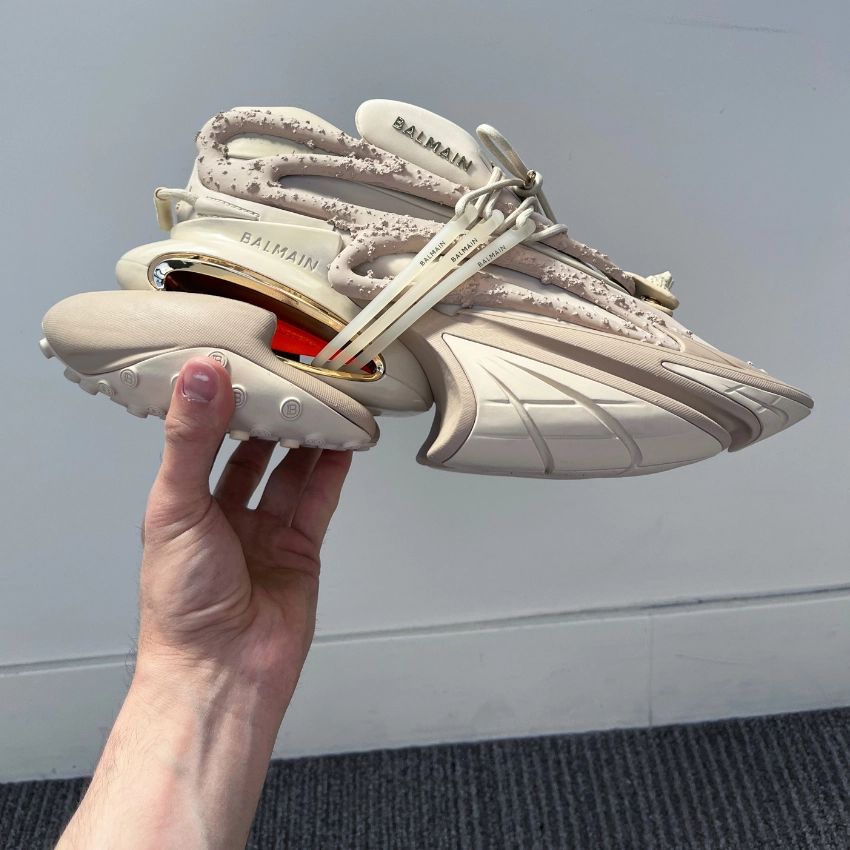 Krem ve bej tonlarında tasarlanmış Balmain spor ayakkabı modeli, dinamik taban yapısıyla yan açıdan görünüm.