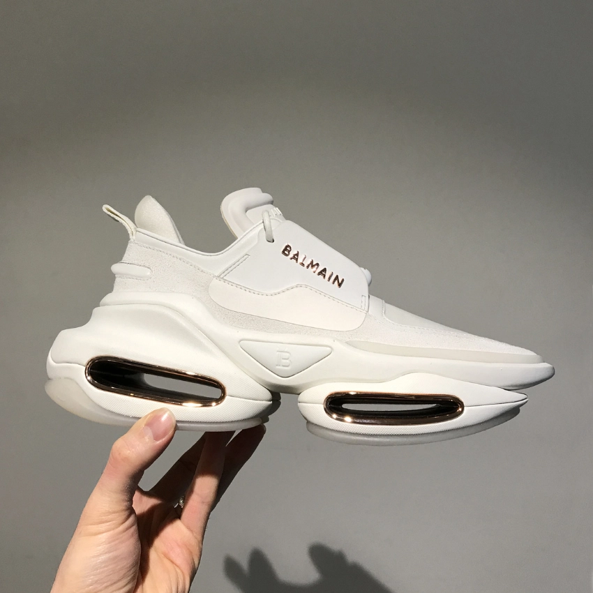Hacimli tabanlı beyaz Balmain sneaker modeli, metal detaylarla tasarlanmış modern spor ayakkabı yan görünüm.