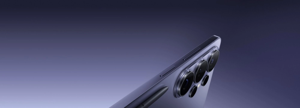 Mor renkteki Samsung Galaxy S26 Ultra akıllı telefonun arka yüzündeki çoklu kamera kurulumu ve kasasına zarifçe entegre edilmiş mor S-Pen, koyudan açığa doğru değişen mor tonlarında degrade bir arka plan üzerinde vurgulanarak gösteriliyor.