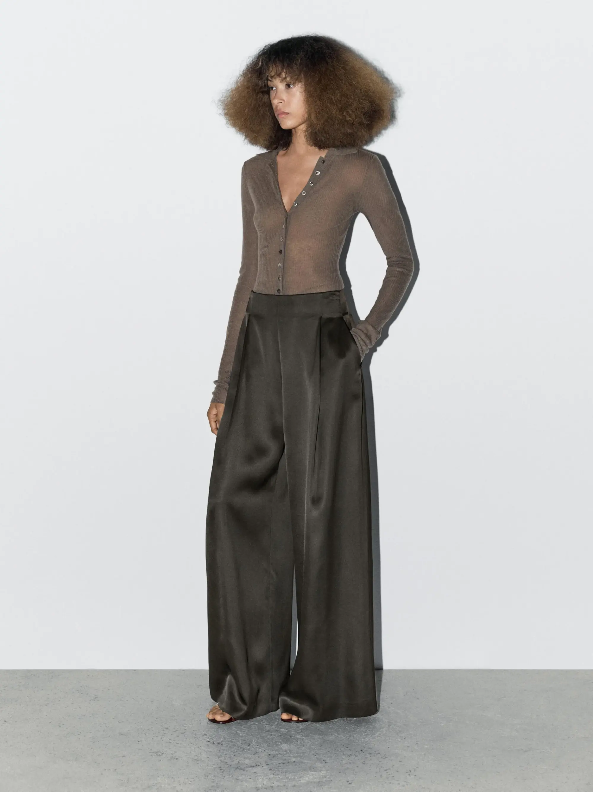 Saten wide leg pantolon ve vücuda oturan triko üst kombinasyonu ile akışkan kumaşın zarif hareketini vurgulayan modern, minimal ve sofistike siluet.