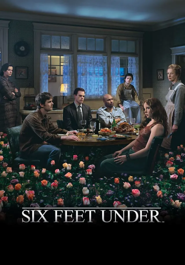 Six Feet Under dizisinde Fisher ailesi üyeleri akşam yemeği masasının etrafında otururken dramatik bir atmosfer içinde birbirlerine bakıyor; ön planda çiçeklerle kaplı bir alan yer alıyor.