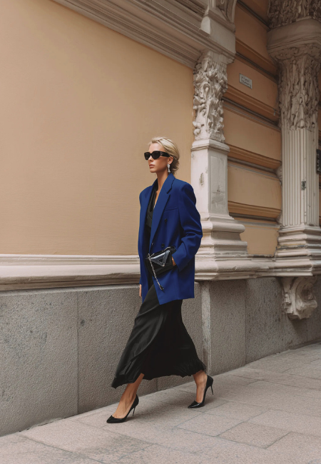 Lacivert blazer ceket ve siyah saten elbiseyi bir arada kullanan model, siyah stiletto ve zincir askılı çantayla siyah ve lacivert kombin önerilerine sofistike, modern ve güçlü bir şehir silueti yorumu katıyor.