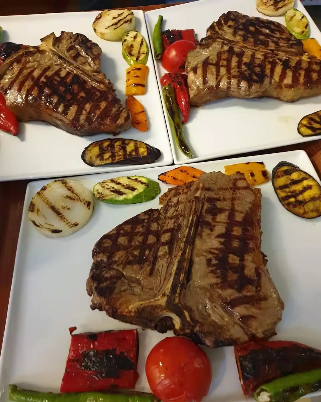Şefin favori et lokantası Beyti'nin ustalığını yansıtan ziyafet; beyaz kare tabaklarda sunulan, belirgin ızgara izli üç büyük T-bone biftek, közlenmiş domates, biber, soğan ve kabak dilimleriyle iştah kabartan bir sunum sergiliyor.