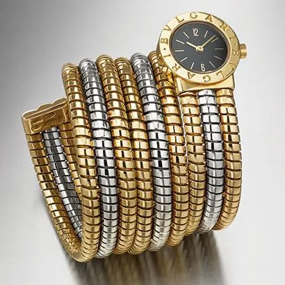 Bir Bvlgari Bvlgari marka, siyah kadranlı, altın ibreli saatin, sarı ve beyaz altının zarifçe iç içe geçtiği, yılanvari ve çoklu sarmallı Tubogas bileziği, 1980'lerin lüks saat işçiliğini gözler önüne seriyor.