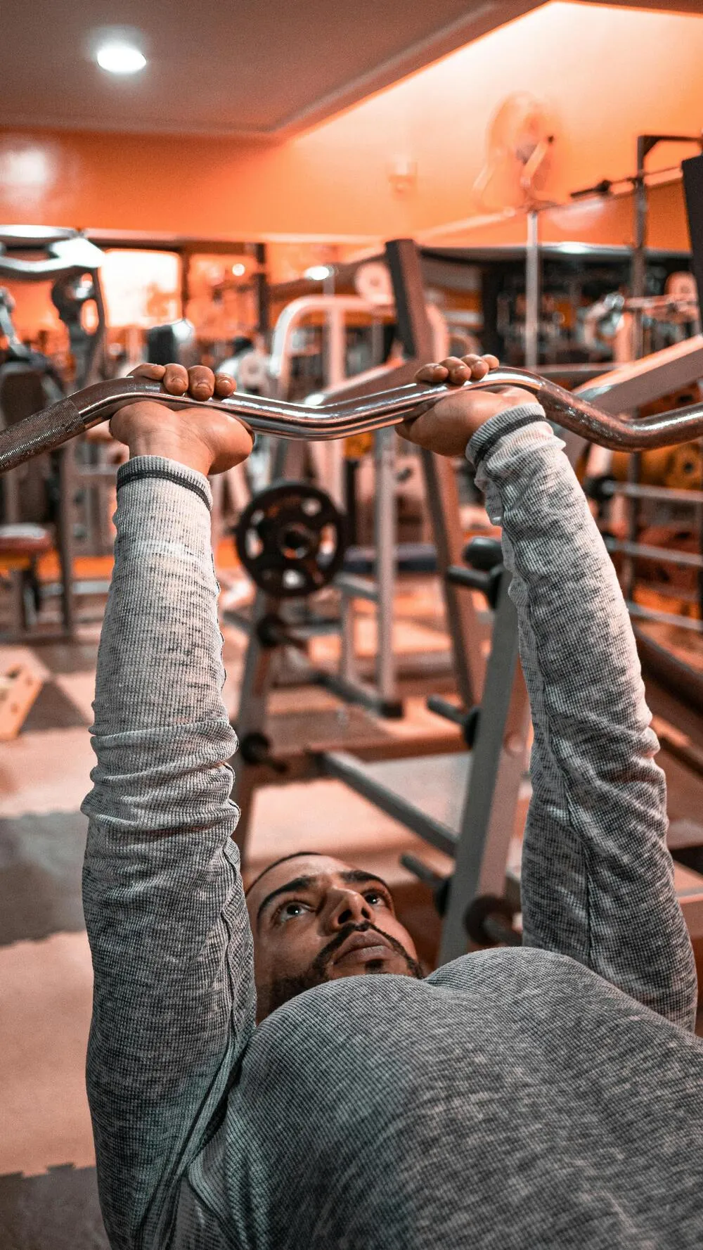 Spor salonunda barbell bench press yapan erkek