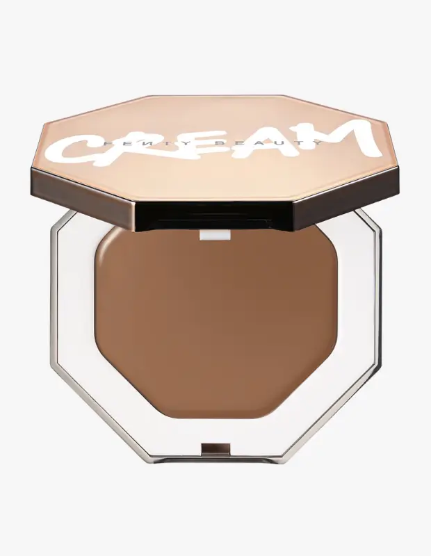 Marka Adı: Fenty Beauty
Ürün Cinsiyeti: Belirtilmemiş
Ürün Tipi: Krem Bronzer
Ürün Sezonsallığı: Yaz
Ürün Çeşidi: Bronzer
Ürün Özellikleri: Altıgen şeklinde şık ve kompakt bir ambalaj içinde sunulan bu krem bronzer, kapağında Fenty Beauty logosu ve belirgin CREAM yazısıyla dikkat çeker. Kapağı açık bej veya gül altın renginde parlak bir yüzeye sahiptir. İçerisinde pürüzsüz, katı bir krem formunda, sıcak alt tonlu orta kahverengi bir ürün bulunur. Cilde kolayca karışarak doğal, güneşten öpülmüş bir bronzluk etkisi yaratmak üzere tasarlanmıştır. Bu ürün, cilde zahmetsizce sıcak ve canlı bir görünüm kazandıran yenilikçi bir formüle sahiptir.
Öne Çıkan Detaylar:
- Altıgen formunda, şık ve kolay taşınabilir kompakt ambalaj tasarımı
- Cilde doğal ve zahmetsiz bir bronzluk veren kremsi, kolay dağılan doku
- Güneşin değdiği noktaları ısıtan, sıcak alt tonlu orta kahve rengi
Kimler Kullanıyor?: Ağır makyaj yerine doğal güzelliğini öne çıkarmayı tercih eden, sağlıklı ve canlı bir ten görünümü arayan kişiler için idealdir. Makyajında zahmetsiz şıklığı benimseyen, yıl boyunca güneşten öpülmüş, sıcak bir ışıltı taşımak isteyenler bu krem bronzerı günlük rutinlerine rahatlıkla dahil edebilir. Minimalist ama etkili bir görünüm arayan, cilt makyajında transparan ve doğal bitişlere öncelik veren herkesin beğenisini kazanacak bir üründür.