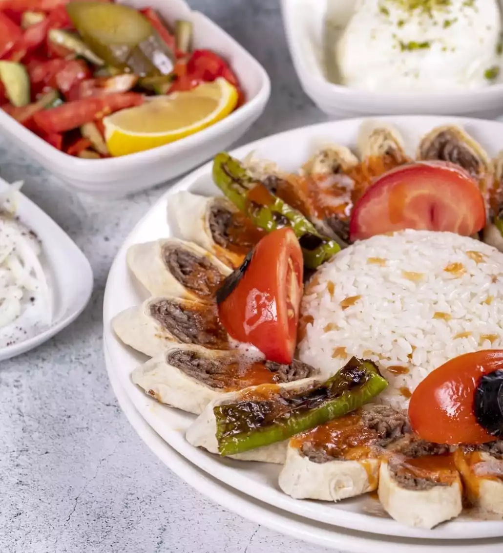 Oggusto: Salvatore Cannetiello – Şeflerin Lezzet Rotaları. Şefin vazgeçilmez lezzet durağı İntiba Döner'i temsil eden tabak: Lavaşa sarılıp dilimlenmiş domates soslu et dönerler, ortasında pilav, közlenmiş biber ve domatesle sunuluyor. Arka planda taze çoban salata ve yoğurt yer alıyor.