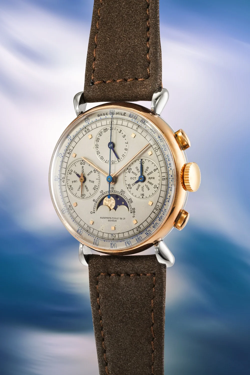 Yakın çekimde görüntülenen bu Audemars Piguet Perpetual Calendar Chronograph Ref. 5503 kol saati, gül rengi altın kasası, kahverengi süet kayışı, ay fazı, gün, ay ve tarih göstergeleri ile karmaşık Sürekli Takvim ve Kronograf mekanizmasını sergileyen beyaz kadranıyla dikkat çekiyor.
