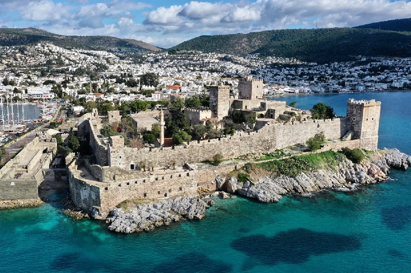 Turkuaz denizin berrak sularıyla çevrili kayalık bir yarımada üzerinde tüm heybetiyle yükselen, eski çağlardan kalma sağlam taş duvarları ve gözcü kuleleriyle çevrili Bodrum Kalesi Müzesi, arkasında bembeyaz evlerin yamaçları süslediği canlı Bodrum şehrini ve yatlarla dolu limanı gözler önüne seriyor.