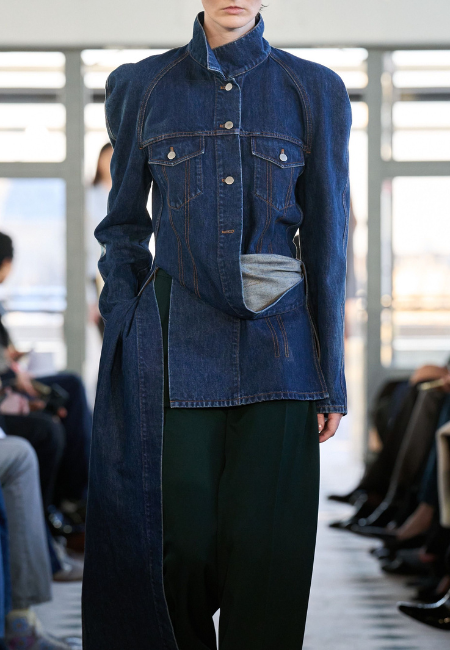 Burc Akyol 2026 Sonbahar Kış defilesinde denim ceket formunda yapılandırılmış üst ve akışkan pantolon kombinasyonu modern terziliği yeniden yorumluyor.