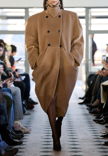 Burc Akyol 2026 Sonbahar Kış podyumunda camel ton oversized palto ve minimal çizgiler zamansız şehir stiline vurgu yapıyor.