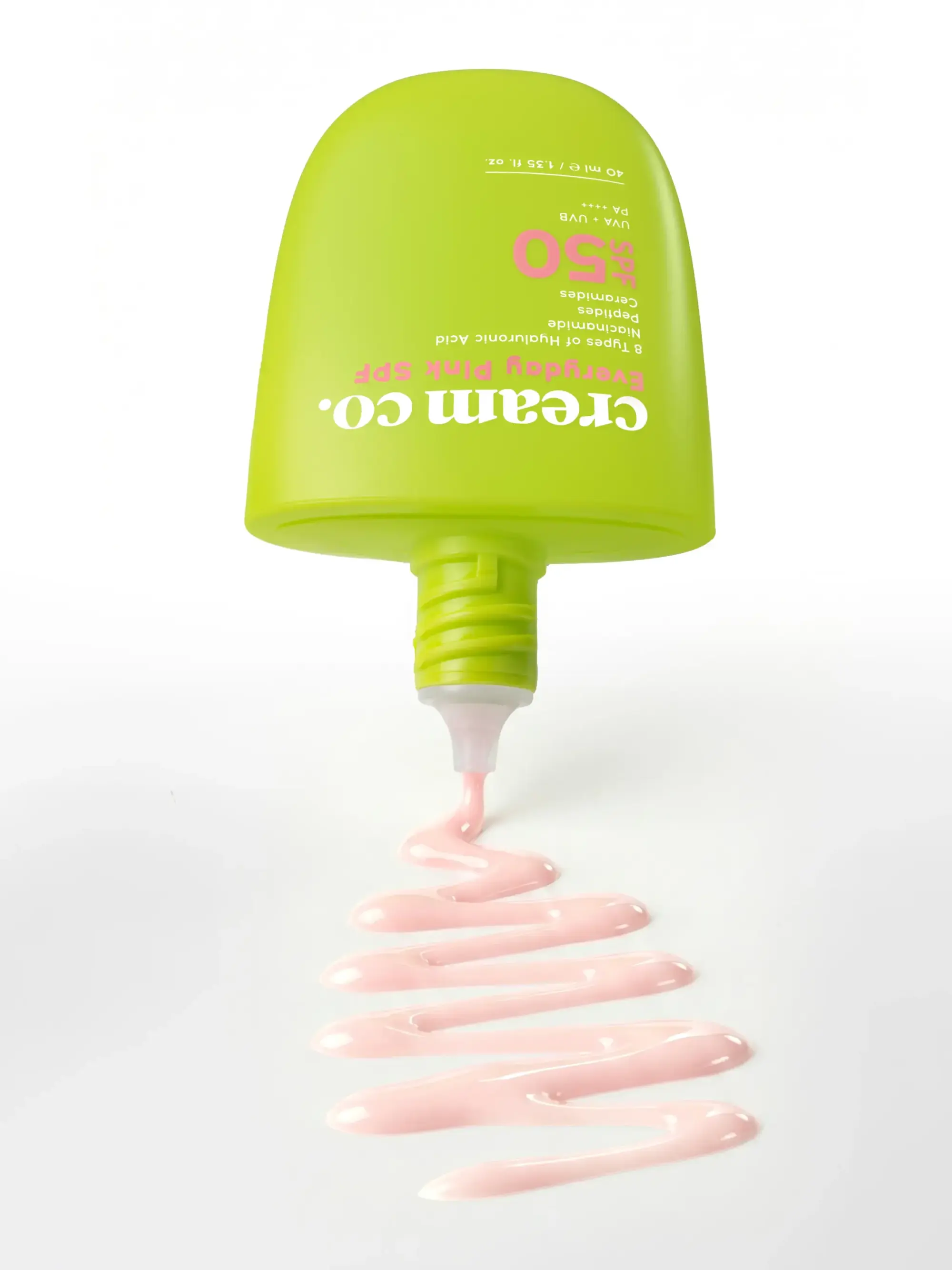 Beyaz bir yüzeyde ters duran, üzerinde Cream Co. Everyday Pink SPF 50 yazan parlak yeşil bir tüpten dışarı akan açık pembe güneş koruyucu kremin dalgalı çizgiler oluşturduğu bu görsel, nisan ayındaki yenilikçi tasarımlar ve taşınabilir güneş koruması çözümlerini öne çıkarıyor.