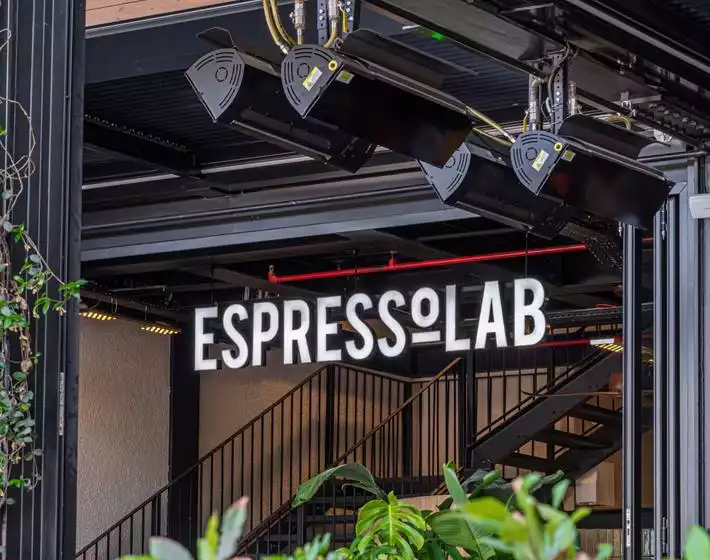 Oggusto - Terminal Kadıköy Rehberi: Lezzet, Alışveriş ve Eğlence Durakları. Terminal'in kahve noktası Espressolab'in endüstriyel tasarımı. Siyah metal merdivenler ve ısıtıcılar altında asılı parlak beyaz tabela, yeşil yapraklar arasından ziyaretçileri kahve molasına davet ediyor.