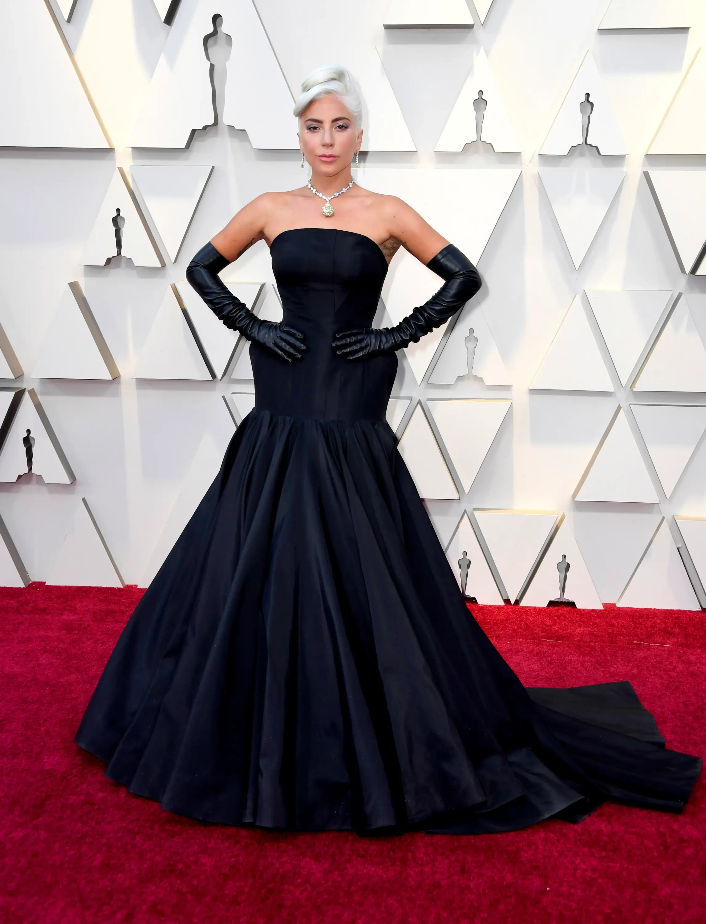 2019 Oscar Ödülleri’nde Lady Gaga, Alexander McQueen imzalı straplez siyah elbisesi, uzun deri eldivenleri ve Tiffany & Co. sarı elmas kolyesiyle klasik Hollywood ihtişamını modern bir yorumla kırmızı halıya taşıyor.