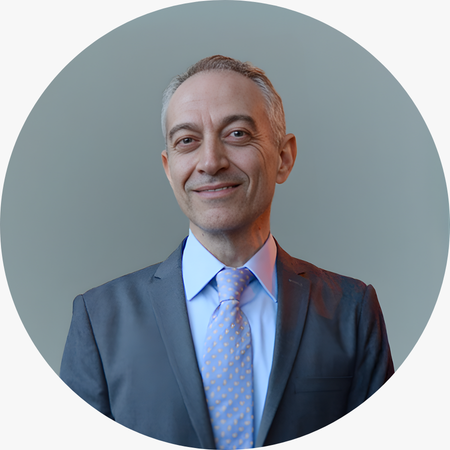 Metin Gürsoy, klasik takım elbisesi ve sade duruşuyla profesyonel ve güven veren bir portre görünümü sergiliyor.