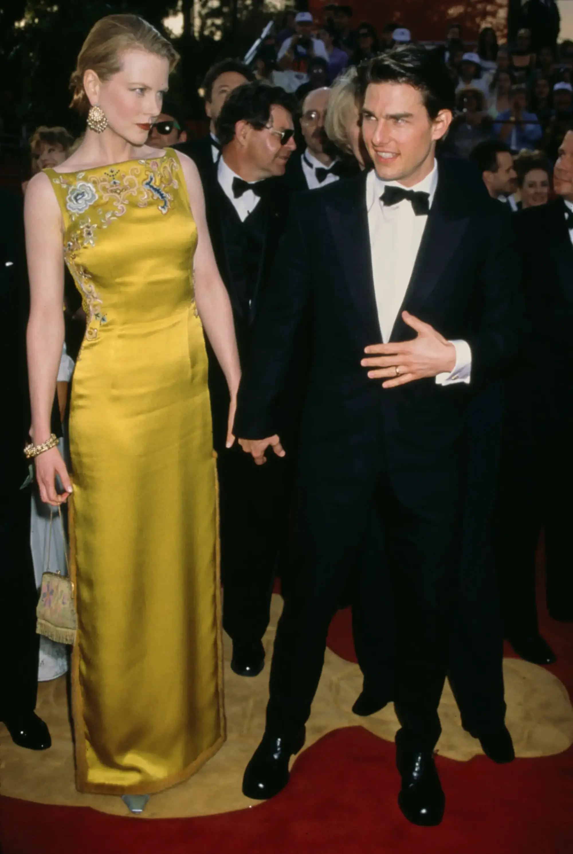 1998 Oscar Ödülleri’nde Nicole Kidman, üzerindeki Çin motifli chartreuse tonlarındaki John Galliano tasarımı Dior elbisesiyle kırmızı halı modasının en unutulmaz görünümlerinden birine imza atarken, yanında Tom Cruise klasik siyah smokiniyle eşlik ediyor.