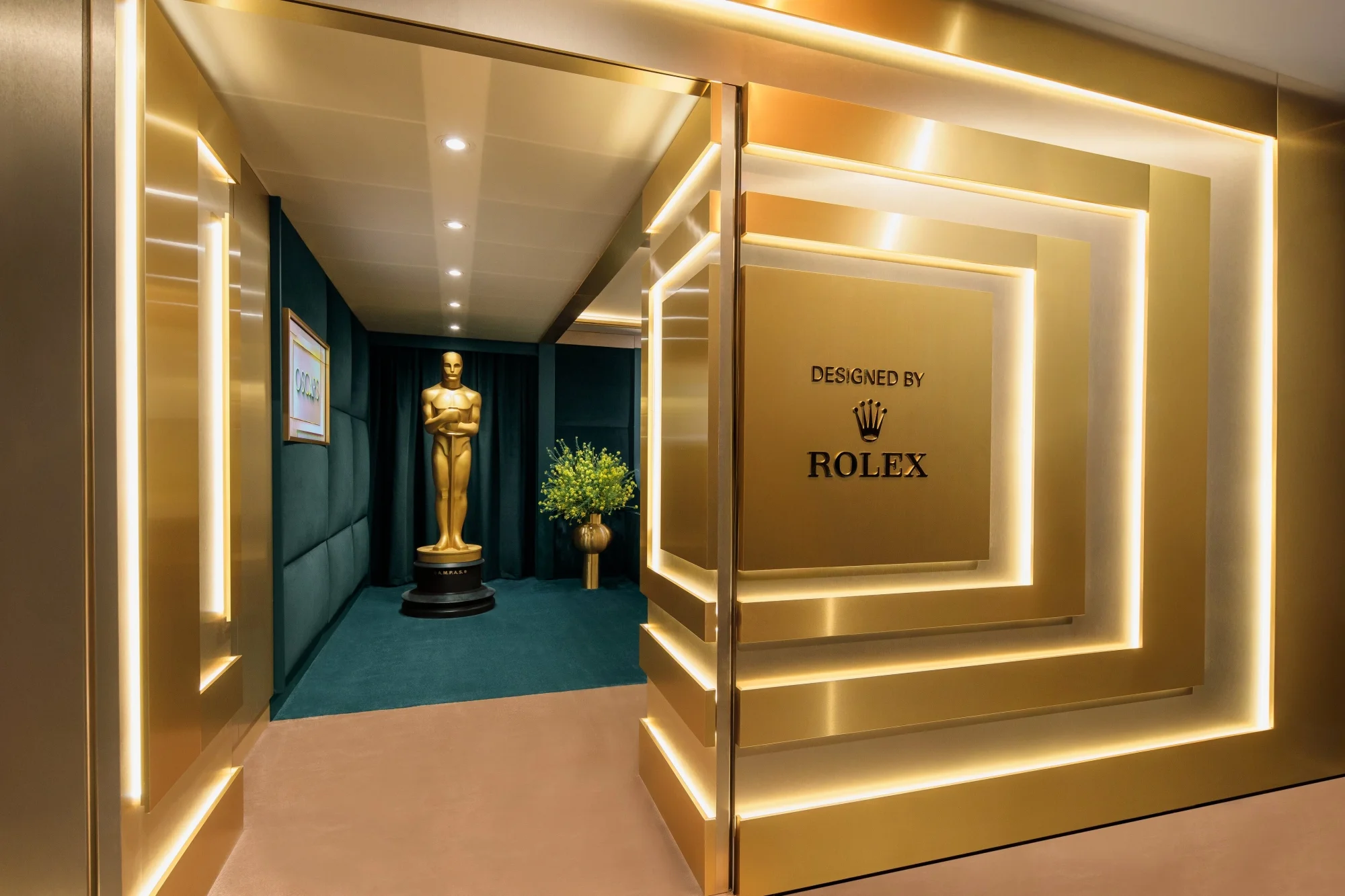 Rolex tarafından özenle tasarlanmış, Oscar Ödülleri'ne özel, altın rengi panellerle aydınlatılmış duvarların modern bir giriş oluşturduğu lüks bir Green Room deneyim alanı içinde, parlak altın Oscar heykelciği ve yeşil halı detayları dikkat çekiyor.