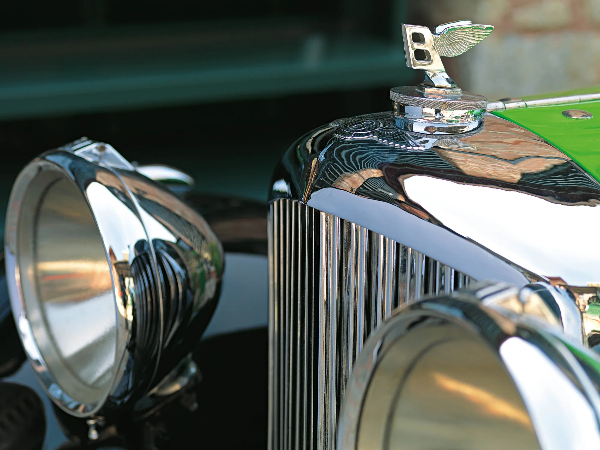 Rahmi Koç Müzesi'nde sergilenen, parlak krom kanatlı B logosu, şık dikey ızgarası ve yuvarlak farlarıyla öne çıkan, 1935 model yeşil bir Bentley klasik otomobilin ön kısmının detaylı yakın çekimi.