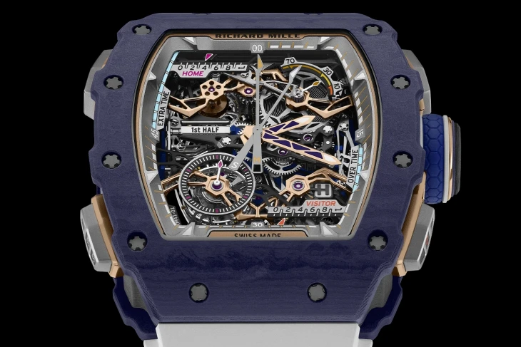 Koyu mavi dokulu kasası ve altın, gümüş, mor detaylarla bezeli iskelet kadranıyla Richard Mille RM 41-01 saati, futbol maçı skorlarını (ev sahibi/deplasman) ve oyunun devrelerini (ilk yarı, uzatma süresi) gösteren özel mekanizmasını siyah bir arka planda net bir şekilde sergiliyor.
