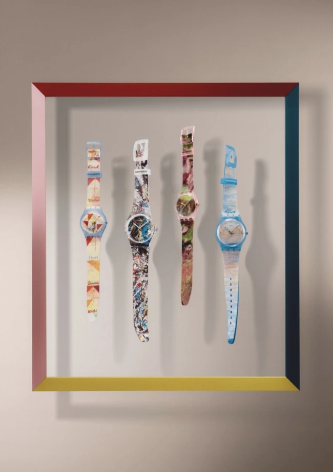 Çeşitli renklerdeki çerçeve içinde, soldan sağa doğru, her biri farklı soyut sanat eserlerini yansıtan tasarımlara sahip dört Swatch Guggenheim Koleksiyonu saati, açık renkli bir duvarda dikey olarak sergileniyor.