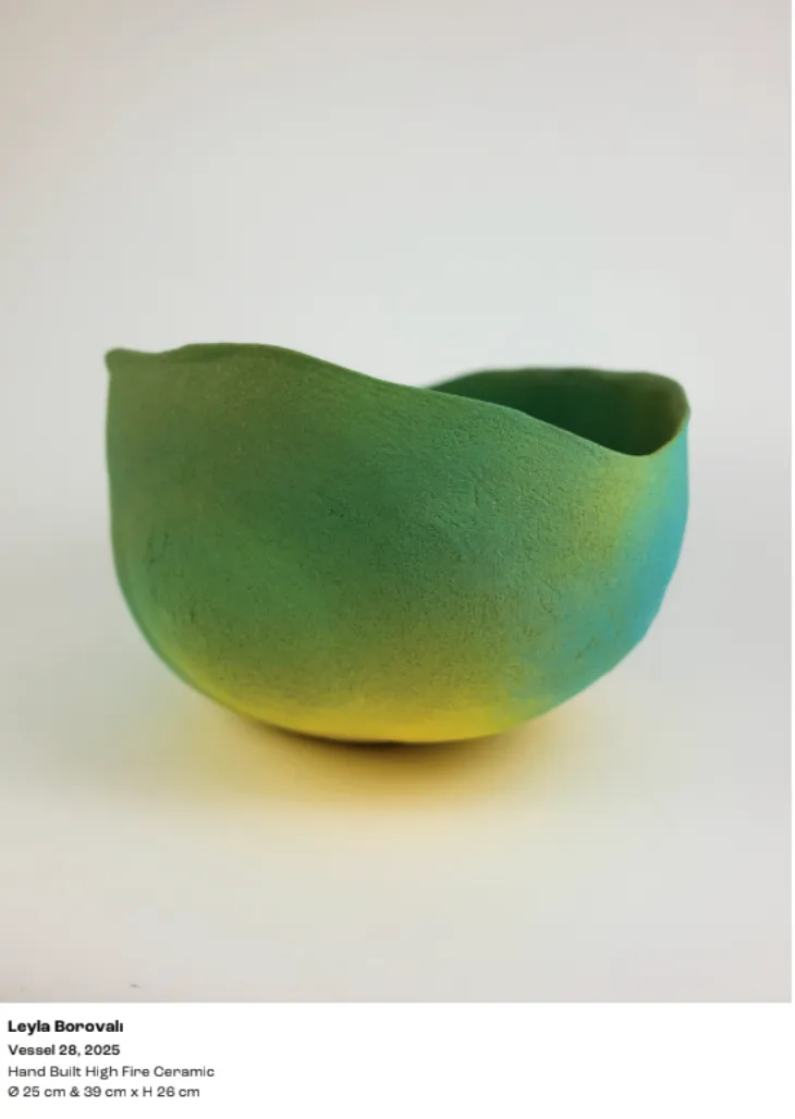 Leyla Borovalı'nın Contemporary Istanbul sergisinde yer alan, doğal ve dalgalı bir ağza sahip, el yapımı yüksek ateşte pişirilmiş seramik vazo Vessel 28, alt kısmında parlak sarıdan orta kısımda koyu yeşile ve üstte turkuaz tonlarına geçiş yapan canlı renkleriyle dikkat çekiyor.