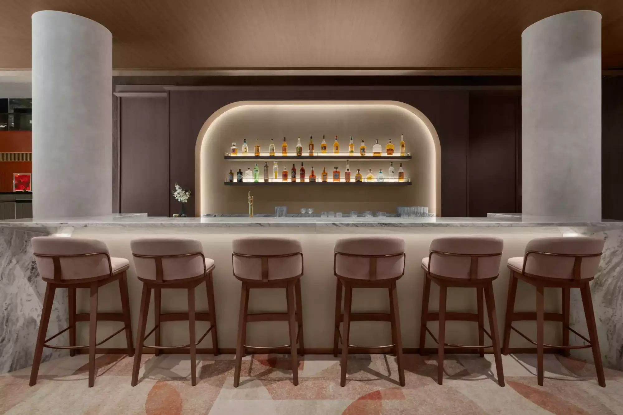 Modern ve zarif Genever Lobby Bar'da, altı adet pembe kadife tabure ile çevrili mermer bar tezgahı dikkat çekerken, arkadaki ışıklandırılmış nişlerde sıralanmış rengarenk içki şişeleri mekana sıcak bir atmosfer katıyor.