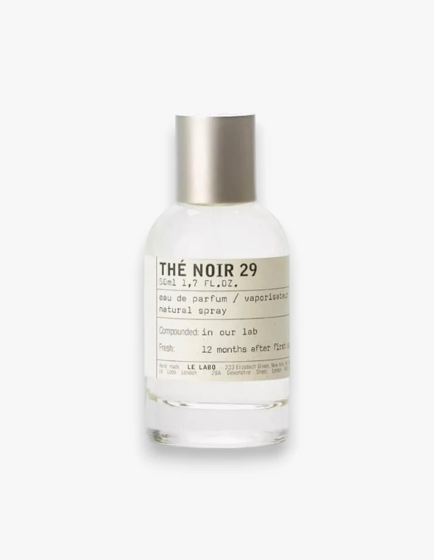 Ortasında beyaz etiketi ve gümüş kapağıyla duran, Le Labo markasının 50 ml'lik Thé Noir 29 eau de parfum şişesi, ürünün zarif ve minimalist tasarımını vurgulayarak siyah çayın derin ve baharatlı notalarını çağrıştırıyor.