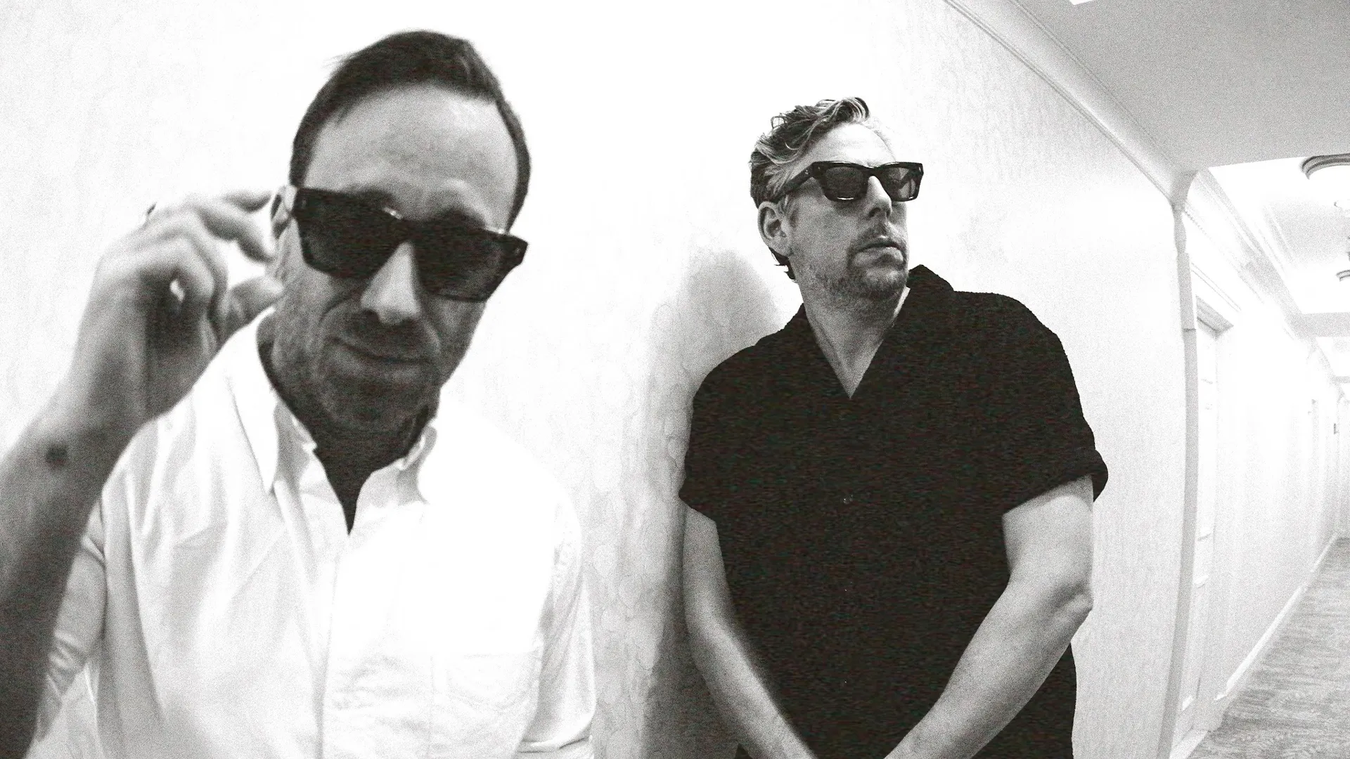 Grammy ödüllü modern blues-rock ikilisi The Black Keys üyeleri Dan Auerbach ve Patrick Carney, siyah beyaz bir otel koridorunda güneş gözlükleriyle, yaklaşan İstanbul konserleri öncesinde karizmatik duruşlarıyla dikkat çekiyor.