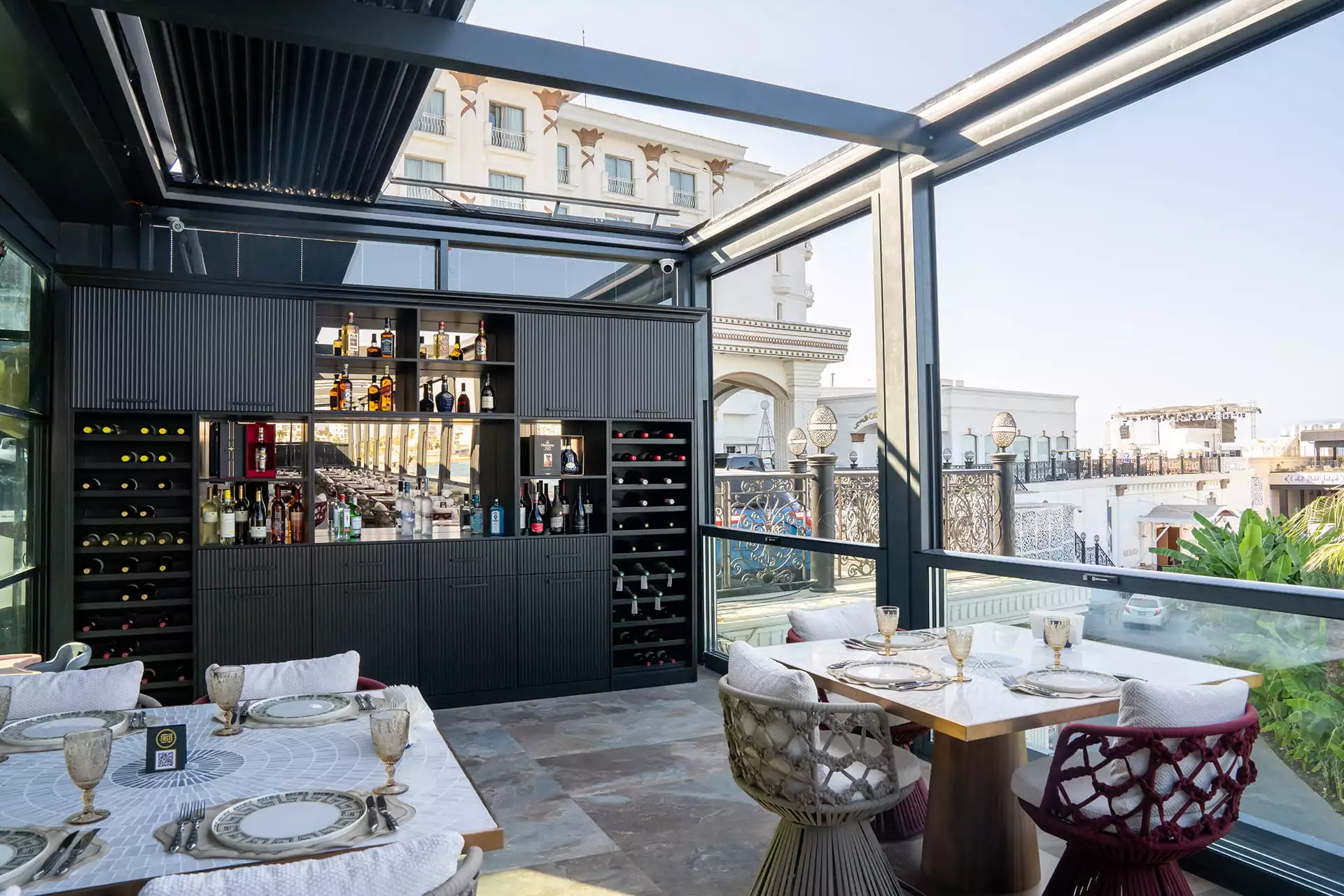 Modern ve lüks bir yemek deneyimi vadeden The Taste Steakhouse terasında, zengin içki çeşitleri sunan koyu renkli bir bar, zarifçe hazırlanmış masalar ve cam tavanın altından görünen güneşli şehir manzarası büyüleyici bir atmosfer yaratıyor.