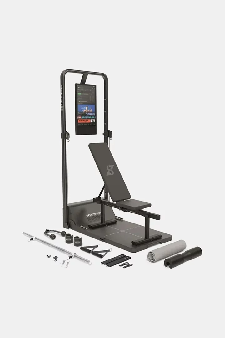 Beyaz bir arka plan üzerinde, fitness egzersiz programları gösteren dijital ekranı, ayarlanabilir egzersiz sehpası ve bir dizi ek aksesuarla tamamlanan, evde kullanım için tasarlanmış gri ve siyah renkli bir akıllı ağırlık istasyonu.
