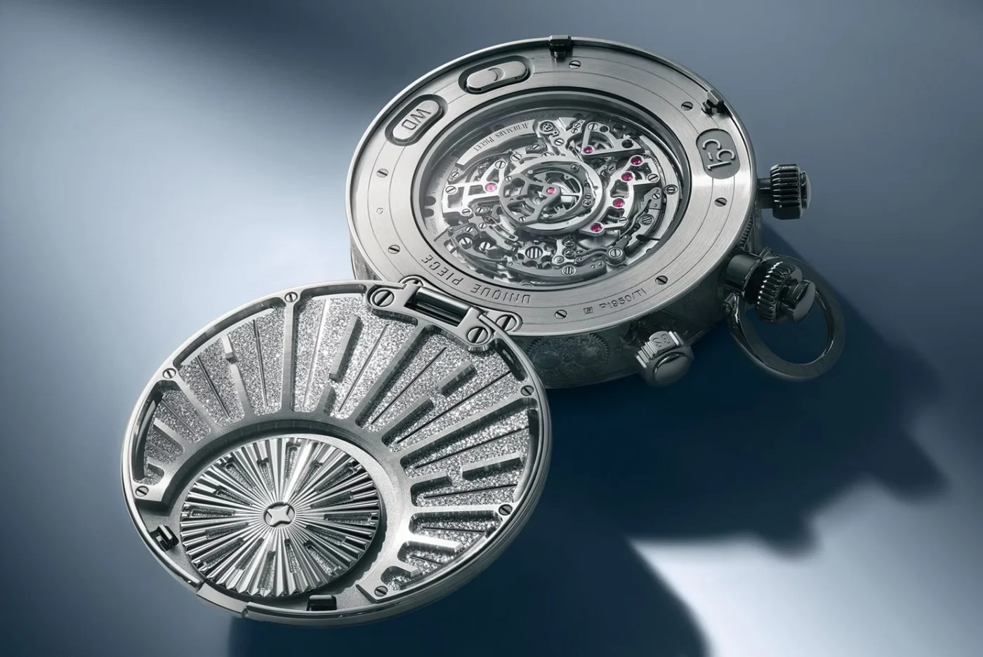 Gümüş renkli Audemars Piguet cep saatinin, açık arka kapağından görünen karmaşık mekanizması parlak yakut taşları ve hassas dişlileriyle öne çıkarken, kapağın iç yüzündeki ışıldayan, dokulu sanatsal desen 150. yıl özel tasarımını vurguluyor.