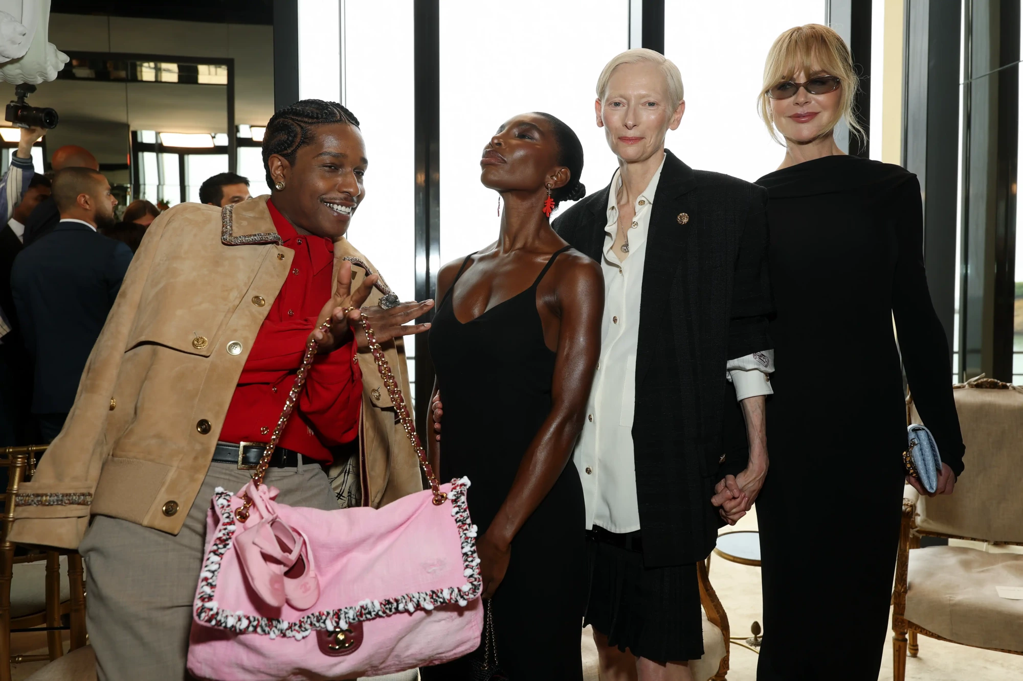 Matthieu Blazy'nin ilk Chanel Cruise koleksiyonu defilesinin ön sırasında, ünlü isimlerden A$AP Rocky pembe bir Chanel çantası tutarken neşeli bir ifadeyle objektife bakıyor, Michaela Coel başını zarifçe kaldırmış, Tilda Swinton ve Nicole Kidman ise el ele poz veriyorlar.