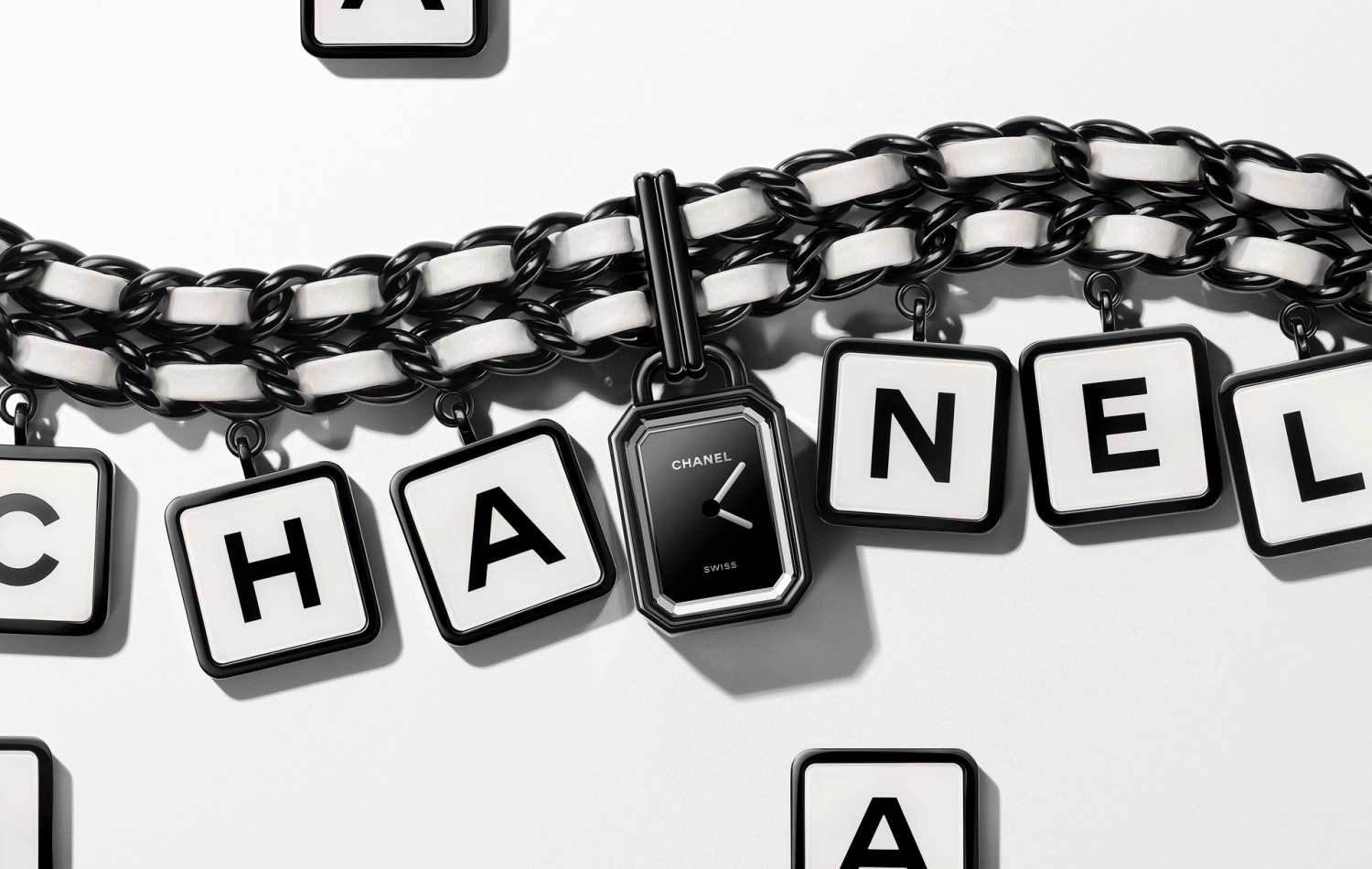 Coco Game Koleksiyonu'na ait, siyah-beyaz deri örgü detaylı zincir kordon üzerinde CHANEL yazısını oluşturan kare harf küpleri arasına yerleştirilmiş, parlak siyah kadranlı ve markanın adını taşıyan zarif bir Chanel Premiere saat.
