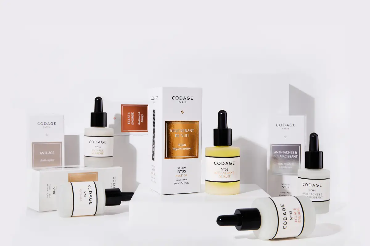 Birkaç farklı renk ve içerik barındıran CODAGE Paris dermokozmetik serum şişeleri ve beyaz kutuları, markanın kişiye özel formülasyon yaklaşımını vurgulayan düzenli bir sergide Anti-Age, Regenerant de Nuit ve Eclat & Energie gibi çeşitli cilt bakımı ürünlerini gözler önüne seriyor.